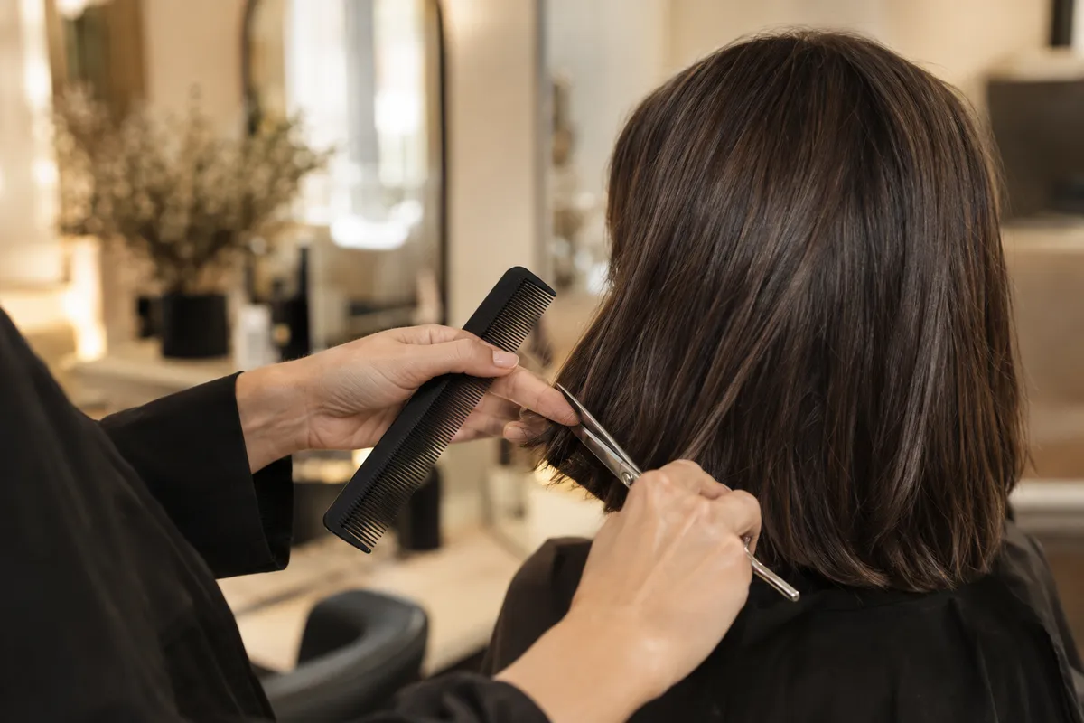Stylist precision-cutting a glossy brunette bob